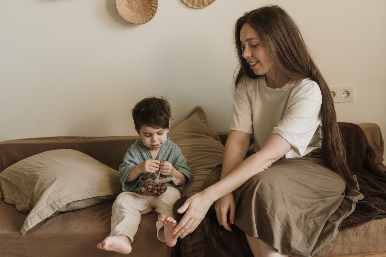 A mother and son sitting together on a sofa, sharing a loving moment.